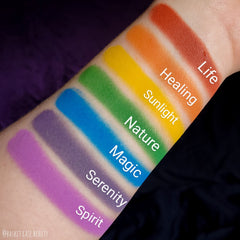 Close-up of rainbow matte eyeshadow palette showing seven vibrant powder pigments in a sleek black case