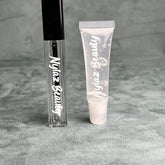 Lip gloss set, clear tubes with white Nylaz Beauty text, on gray surface