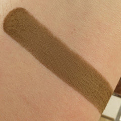 Brown swatch of makeup on skin, showing color and texture of product.