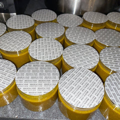 Close-up of golden turmeric foaming scrub with creamy texture in sleek white pump bottle, showcasing vibrant formula