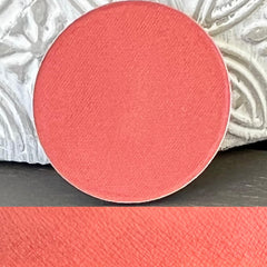 Eye shadow pan, coral matte color, round pressed powder compact, close-up view