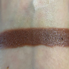 Close-up of fingertips applying shimmery bronze eyeshadow from palette to eyelid crease