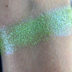 Close-up of fingertips applying shimmery bronze eye shadow from the palette onto eyelid