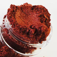 Eye makeup, copper shimmer eyeshadow in a clear glass jar, with loose powder visible