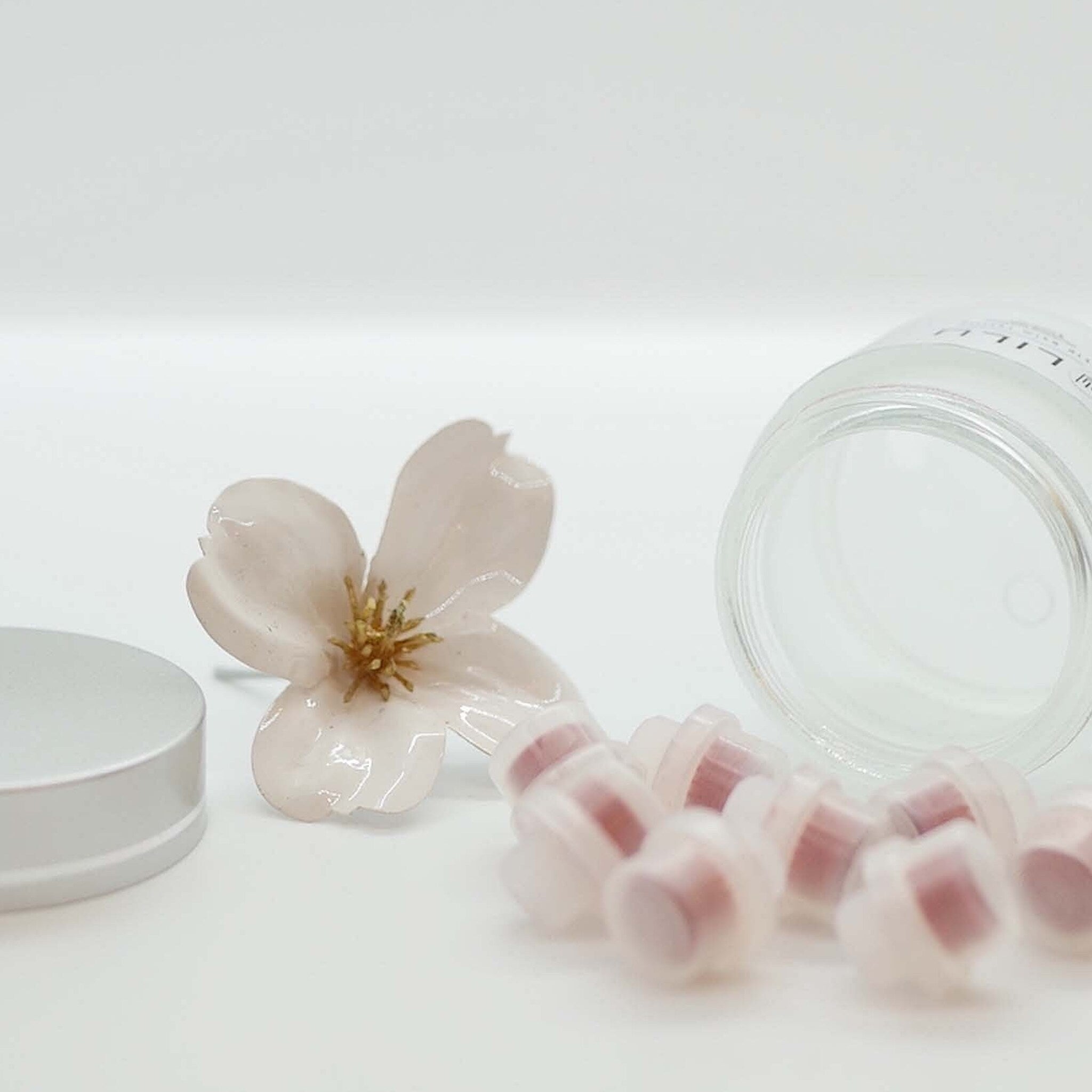 Lip balm refills, pink and clear plastic, with flower and container visible