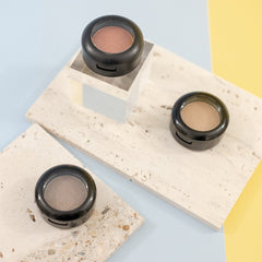 Side angle view of Sunset Peach eyeshadow pan showing sheer orange sequin shimmer in compact