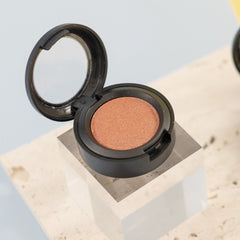 Sunset peach eyeshadow pan with sheer orange sequin shimmer in compact packaging