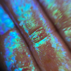 Side view of Triton’s Garden multichrome flakes eye shadow showcasing iridescent blue-green shift in jar
