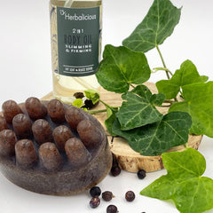 Body oil bottle, clear liquid, green and white label, Herbalicious brand, with green leaves and brown soap