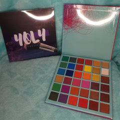 Close-up of artist applying shimmery bronze eyeshadow from palette with blending brush