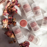 Lip balms in clear tubes with rose-tinted balm, "All Day" text, and dried rose petals