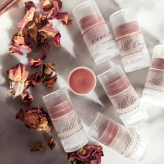 Lip balms in clear tubes with rose-tinted balm, "All Day" text, and dried rose petals