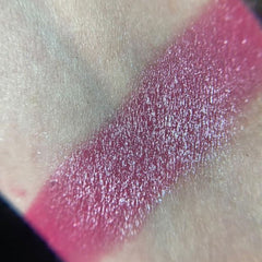 Close-up of fingertips applying shimmery plum eyeshadow from the Razzmatazz palette to eyelid crease