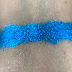 Close-up of fingertips applying shimmery taupe eyeshadow from palette to eyelid crease