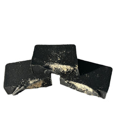 Black soap bars with speckled texture and rough edges, stacked together