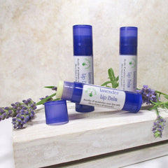 Lip balm tubes, blue and white with lavender, on a white wooden crate with lavender sprigs