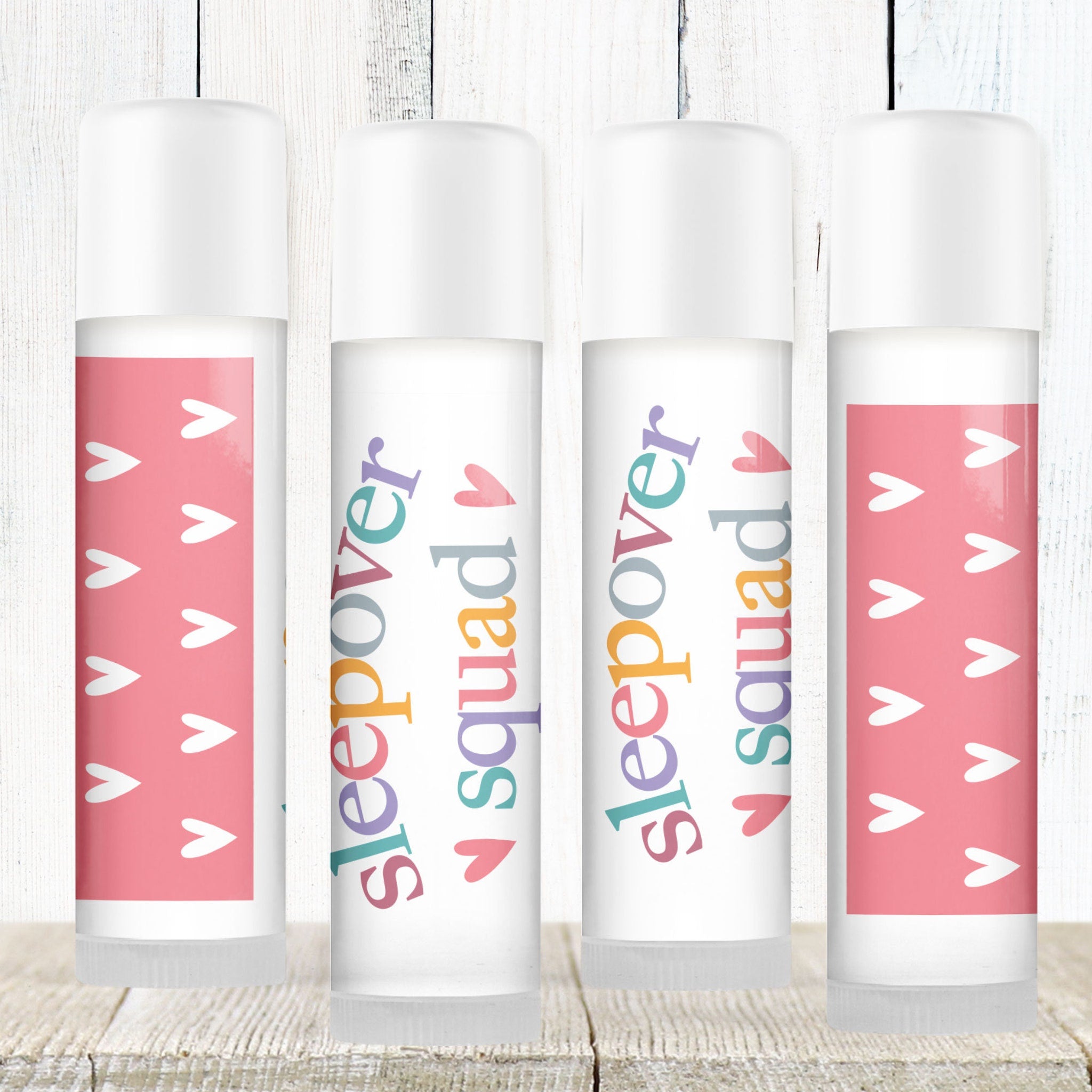 Lip balms with white tubes, pink heart pattern, and "Sleepover Squad" text
