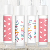 Lip balms with white tubes, pink heart pattern, and "Sleepover Squad" text