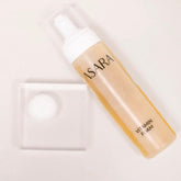 Facial cleanser bottle, transparent and white, with "SARA" text, resting on clear block