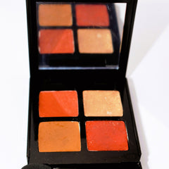 Eyeshadow palette with orange and peach shades in a black compact with mirror