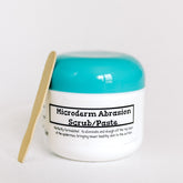Microderm Abrasion Scrub white jar with teal lid and wooden spatula next to it