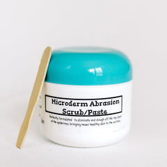 Microderm Abrasion Scrub white jar with teal lid and wooden spatula next to it