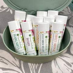 Lip balms in white tubes with colorful labels, displayed in a green container, Green Daffodil brand