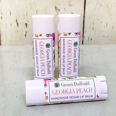 Lip balm tubes with white caps, floral pattern, and Green Daffodil Georgia Peach label