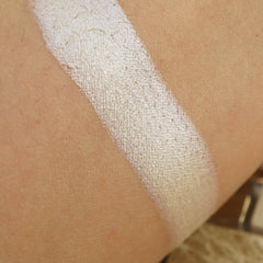 Highlighter swatch, white shimmer on skin, diagonal application on arm