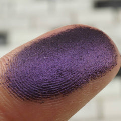 Purple eyeshadow swatch on finger, showing color, texture, and application