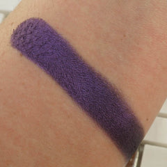 Purple eyeshadow swatch on arm, matte finish, textured appearance, for makeup application