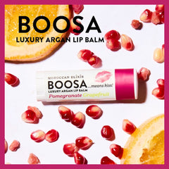 Lip balm tube with BOOSA brand text, white and pink packaging, surrounded by pomegranate seeds