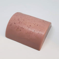 Soap bar with pink color, speckled pattern, and curved top edge