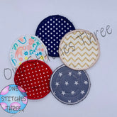Reusable cotton pads in assorted colors, patterns, and styles, with One Stitches Three logo visible
