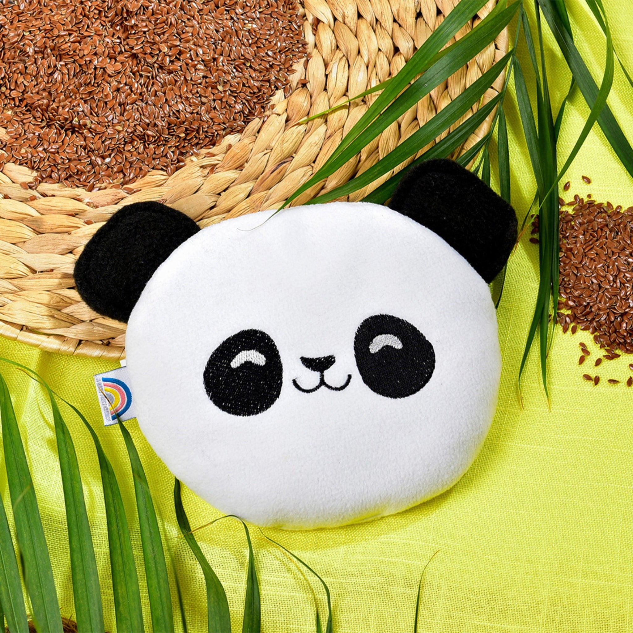 Heating pad, panda-shaped white plush with black accents, on yellow fabric with greenery