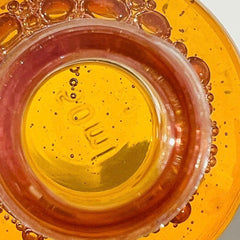 Yellow and orange glass with bubbles and a red rim, close-up view