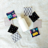 Makeup remover pads with geometric, radio and solid fabric, arranged with bottle on towel
