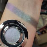 Eyeshadow swatch with multichrome green, silver, and pinkish-red shades on arm, Bruxa eyeshadow visible
