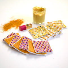 Reusable face cloths with orange, purple floral pattern and white trim, and yellow fabric options