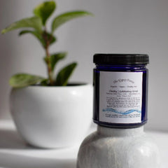 Exfoliating scrub jar with blue glass, black lid, and white label, "The Gypsy Forest" brand