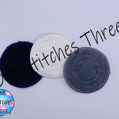 Round fabric pads in navy, white, and gray with One Stitches Three text