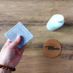 Reusable face pad held by hand, light blue fabric, square shape, wood background