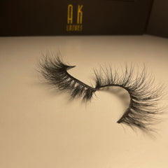 False eyelashes, black synthetic fibers, curved style, with AK Lashes branding on packaging