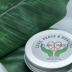 First aid vegan salve, silver metal tin with Plant Magic label, on green leaf background
