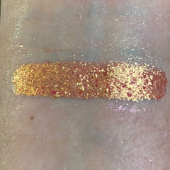 Close-up of shimmering holiday eye shadow palette with gold, silver, and ruby red shades in circular pans