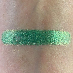 Close-up of shimmering fir green eyeshadow pan showing rich pigmentation and smooth texture