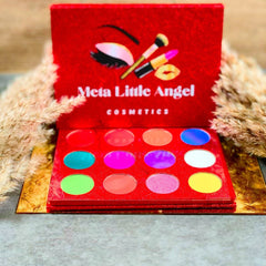 Open rectangular palette displaying 12 shimmering eyeshadow shades in glittery neutrals, brights, and deep tones