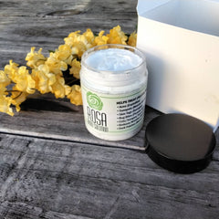 Body solution jar with white cream, black lid, and "ROSA" label on wood surface
