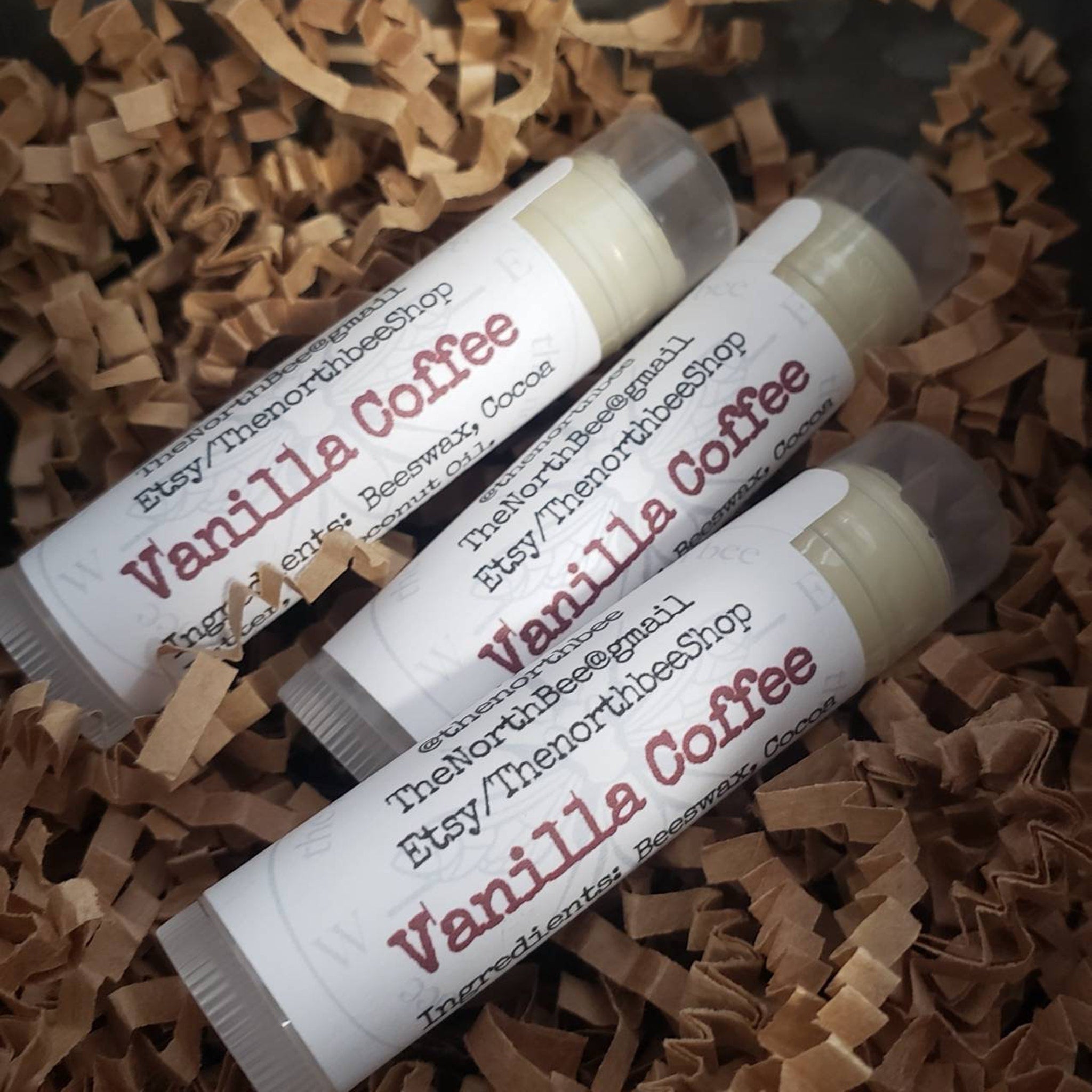 Lip balms with white labels and Vanilla Coffee text, in brown shredded paper, The North Bee brand