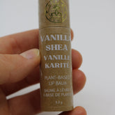 Lip balm tube in brown cardboard with white text, held in hand, GLEAM & GLOW logo visible